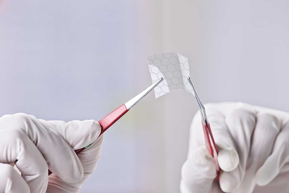 tweezers holding thin material second image for an insight into graphene hands holding material