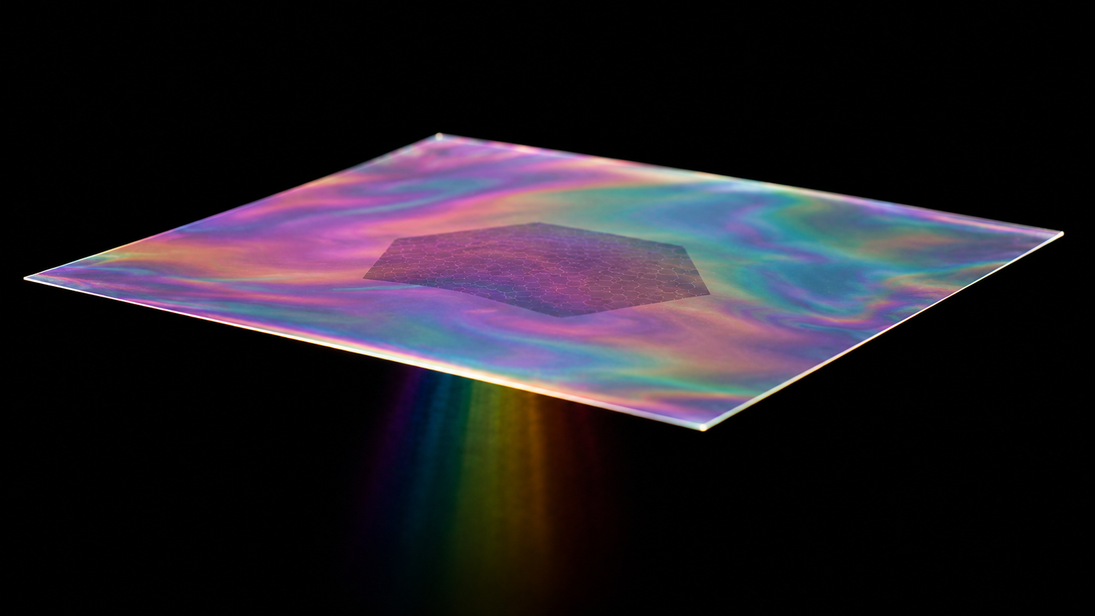 An iridescent ultrathin membrane floating on a black background with a faint darker hexagonal atomic patch resting on it and a narrow spectral rainbow refracted beneath