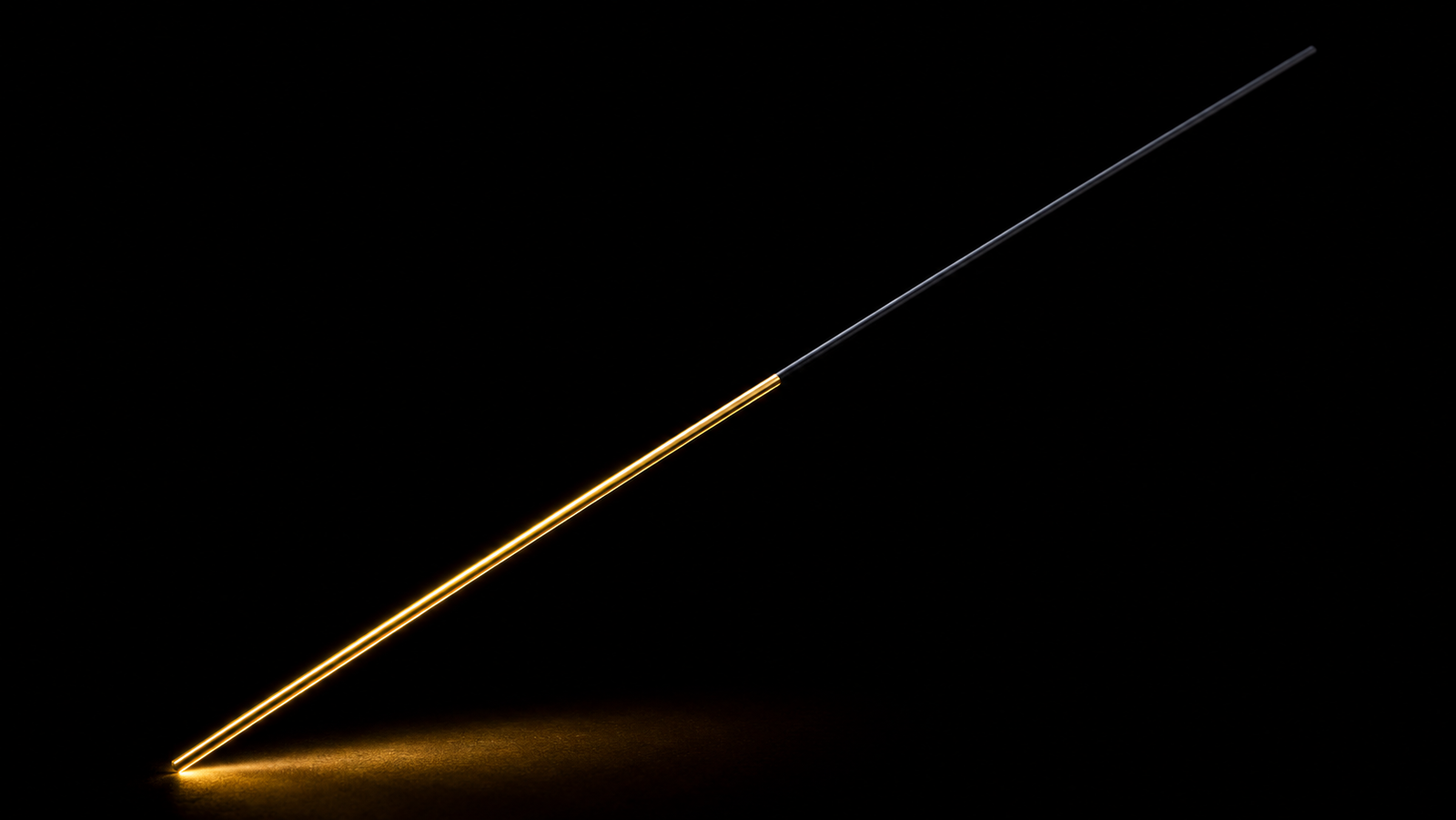 A single straight fiber crossing a black frame diagonally, its lower half sheathed in mirror-bright gold, its upper half matte black