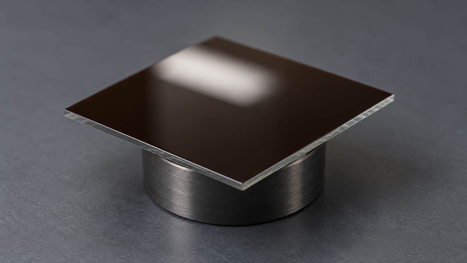 A small glass substrate with a smooth, dark, mirror-like perovskite film on a spin coater chuck